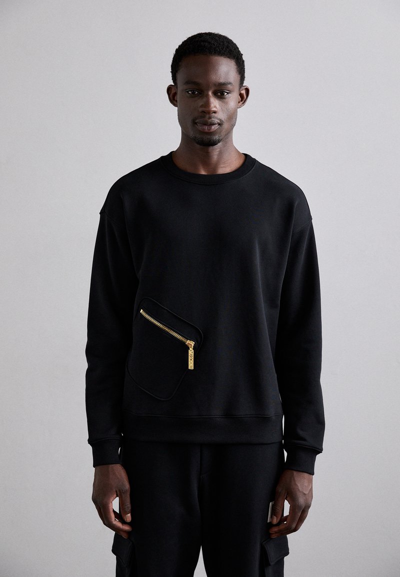 Čierna mikina vyrobená z bavlny s okrúhlym výstrihom, s prednou vreckom na zips v kontrastnom dizajne. Hladká textúra.