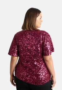 Maglietta a maniche corte rivestita di paillettes bordeaux, con una vestibilità comoda e un collo rotondo. Il retro è solido e con una texture liscia.