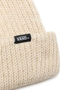 Gorro de punto en color crema, con diseño de puño y una etiqueta de logo negra de Vans. El material parece suave y texturizado con un patrón de tejido suelto.