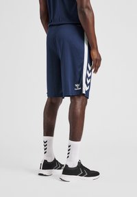 Marina träningsshorts med vita sidostråk och fiskbensmönster. Tillverkade av lättviktsmaterial, med elastisk midja.