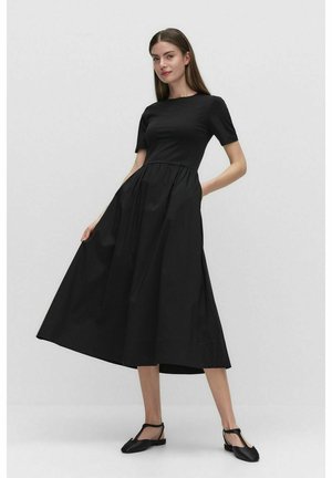 Zwarte jurk met korte mouwen, aansluitend bovenlijf en een uitlopende rok tot op de knie. Gemaakt van gladde stof met een minimalistisch ontwerp.