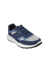 Zapatilla deportiva azul con parte superior de malla y gamuza, que presenta una entresuela blanca, suela de goma y cordones tonales. Acentuada con detalles en negro.