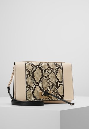 Beige en zwarte crossbodytas met een voorkant met slangenhuidmotief, een goudkleurige sluiting en een zwarte leren riem met gouden kettinkje detail.