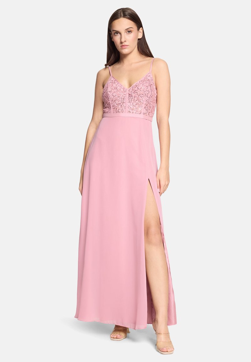 Longue robe rose avec un corsage ajusté en dentelle et des bretelles spaghetti. La jupe présente une fente haute jusqu'à la cuisse et une texture de tissu fluide.