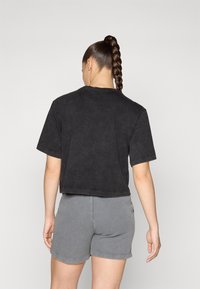 Black cropped t-shirt with short sleeves and a round neckline, paired with gray ribbed shorts, featuring a plain design and soft texture.