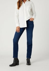 Witte, gestreepte langemouwen shirt met knoopsluiting, gecombineerd met donkerblauwe jeans en zwarte héél-laarsjes. Casual pasvorm, gladde textuur.