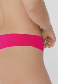 Rosa, nahtloser Bikini-Unterteil mit glatter Textur und breitem Bund, der ein minimalistisches Design zeigt.