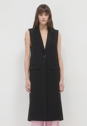 Gilet nero senza maniche con scollatura a V profonda, chiusura frontale con bottoni e due tasche laterali, caratterizzato da un design pulito e sartoriale.