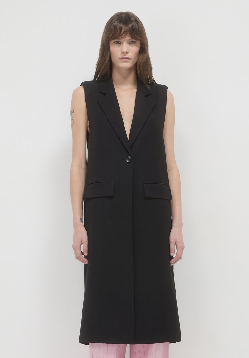 Schwarze ärmellose Weste mit tiefem V-Ausschnitt, vorderem Knopfverschluss und zwei Seitentaschen, die ein sauberes, maßgeschneidertes Design aufweist.