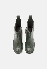 Botines de charol verdes con paneles laterales elásticos, punteras redondeadas y tiradores en la parte trasera para facilitarn el calce. Acabado suave y brillante.