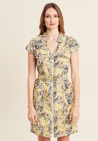 Kurzes Kleid aus leichtem Stoff mit floralem Muster in Gelb, Grün, Schwarz und Rot, mit Reißverschluss vorne und Taillengürtel.
