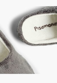 Chaussons gris en peluche avec une doublure intérieure douce et une étiquette de marque cousue portant la mention "Pisamonas". Design à orteils ronds et texture moelleuse.