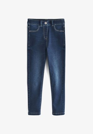 Jeans de mezclilla de color azul oscuro con un corte ajustado, que cuentan con un cierre frontal de botones y bolsillos laterales, combinados con zapatillas suaves de colores variados.