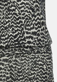 Svart och vit abstrakt djurmönstrad tyg med skräddarsydd sömdetalj vid midjeområdet av plagget.