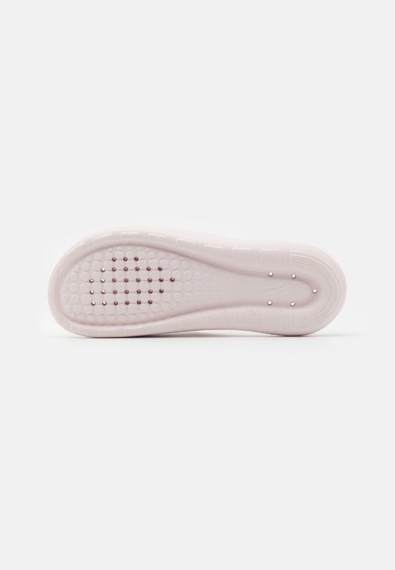 Semelle de chaussure rose clair avec une surface texturée présentant des motifs circulaires et en grille, un détail de logo subtil et un bord lisse et arrondi.