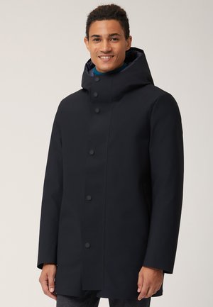 Cappotto impermeabile di colore blu navy con colletto alto, cappuccio regolabile e chiusura a bottoni a scatto. Tessuto liscio con design minimalista.