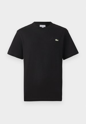 Camiseta de algodón negra con cuello redondo. Presenta un pequeño logo de Lacoste bordado en verde y blanco en el pecho. Mangas cortas, corte regular.
