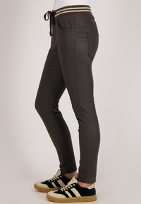 Slim-fit, donkergrijze broek met een trekkoord in de taille, voorzien van twee zakken aan de voorkant en een achterzak. Gelaagd materiaal met een gladde afwerking.
