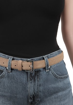 Tan suede belt with a rectangular silver buckle, worn over high-waisted blue jeans, featuring a textured ribbed black top underneath.