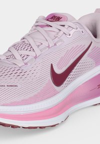 Ανοιχτό ροζ αθλητικό παπούτσι Nike με σκουρόροζ Swoosh, στρωμένη ροζ-λευκή σόλα και ετικέτα "RUN" στη γλώσσα.