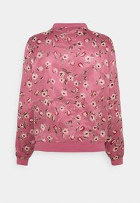 Blusa floreale rosa realizzata in tessuto leggero e semi-trasparente. Presenta una scollatura rotonda, polsini a coste e motivi floreali in crema, rosso e verde.