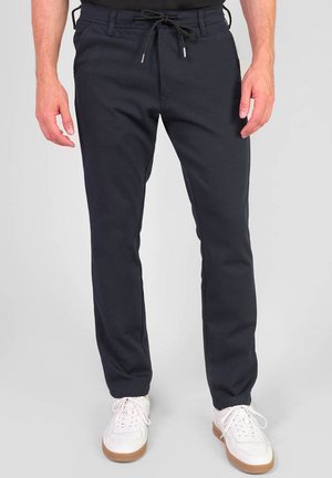 Navy jogger pants with an elastic waistband and adjustable drawstring. Made of soft fabric, featuring a slim fit and side pockets, paired with white sneakers.