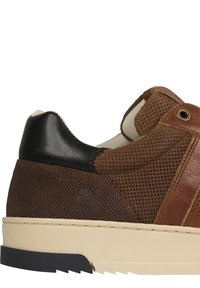 Sneaker marrone con tomaia in mesh testurizzata e accenti in pelle liscia. Presenta un cappuccio del tallone nero, suola beige e strisce in pelle marrone.