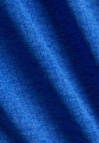 Blauer Stoff mit einer strukturierten Musterung aus kleinen Perforationen und diagonalen Falten, die Schatten und Lichtreflexe erzeugen.