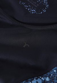 Mornarska sportska tkanina glatke teksture, s plavim prskanjem i suptilnim logotipom. Detalji u obliku zakrivljenih šavova na rubovima.