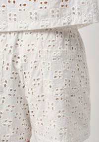 Witte shorts van oogjesstof met ingewikkelde uitsnijdingen, een gestructureerd oppervlak, een losse pasvorm en een zijzakje.