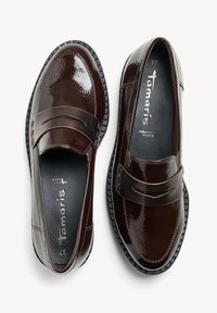 Mocassins en cuir verni brun avec un bout arrondi et une sangle décorative sur le devant. Côtés texturés et semelles en caoutchouc noir.