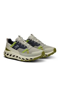 Leichte Sportschuhe mit einem grauen Mesh-Obermaterial und schwarzen sowie grünen Akzenten, dicker weißer Zwischensohle mit strukturiertem Dämpfungseinsatz und abgerundetem Zehenbereich.