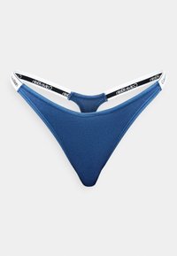 Niebieski bawełniany string z cienką białą gumką z czarnym napisem "Calvin Klein". Gładka tekstura, minimalny fason.