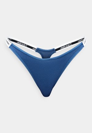 Modré bavlněné tanga s tenkým bílým pasem, na kterém je černý text "Calvin Klein". Hladká textura, design s minimálním pokrytím.