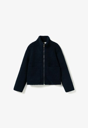 Veste en fausse peau de mouton bleu marine avec col montant, fermeture éclair à l'avant, et deux poches plaquées. Coupe carrée et tissu texturé.