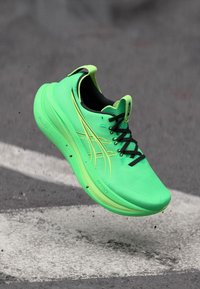 Neon-grüne Laufschuh mit schwarzen Schnürsenkeln, einem strukturierten Obermaterial und einer dicken Sohle. Verfügt über ein markantes gelbes Akzentdesign an der Seite.