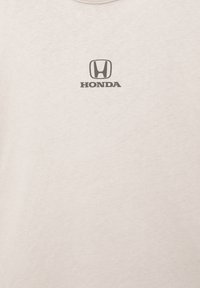 Cremefarvet bomulds t-shirt med rund hals og et sort Honda-logo centralt på brystet. Blød tekstur med en glat overflade.