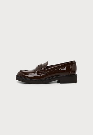 Tumepruun läikiv nahast loafer madala kontsa ja õmmeldud detailiga ühevärvilisel heledal taustal.
