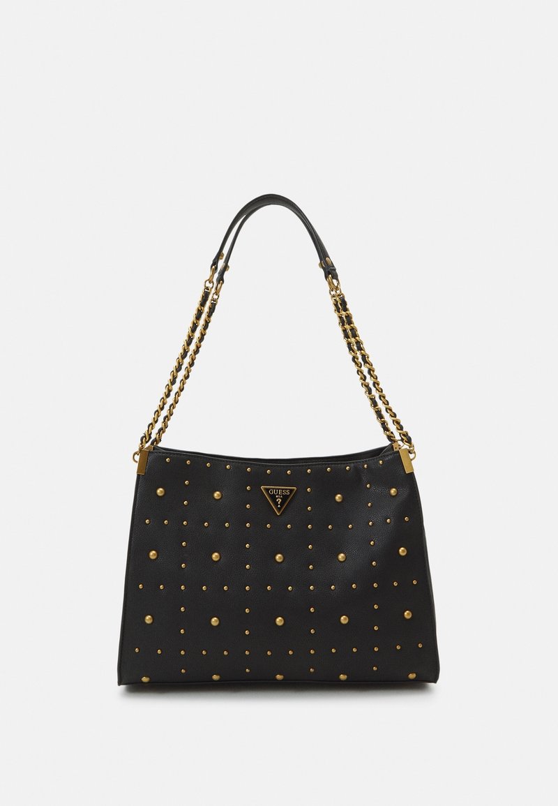 Sac à main en cuir noir avec des détails en clous dorés et des anses en chaîne, doté d'une petite plaque triangulaire du logo Guess au centre.