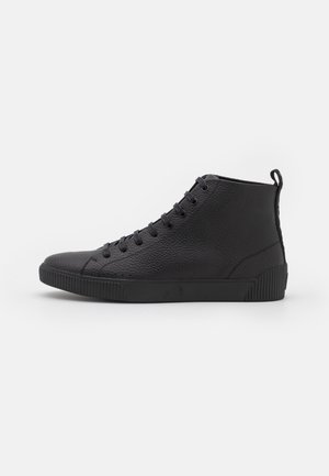 Baskets montantes noires en cuir texturé, devant lacées, semelle en caoutchouc et languette au talon, présentées en profil latéral sur fond blanc.
