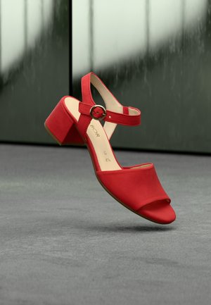 Rote Sandalette mit offenem Zehenbereich, Knöchelriemen und rundem Schnallenverschluss. Hergestellt aus glattem Material mit klobigem Absatzdesign.