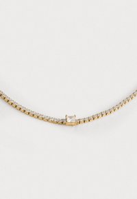 Collana tono oro con catena flessibile, caratterizzata da piccoli cristalli trasparenti e un centrale pietra quadrata, che crea un aspetto delicato e raffinato.
