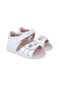 Sandalias de piel blanca con correas ajustables de Velcro, recortes en forma de corazón, plantillas rosas y una suela de goma blanca flexible.