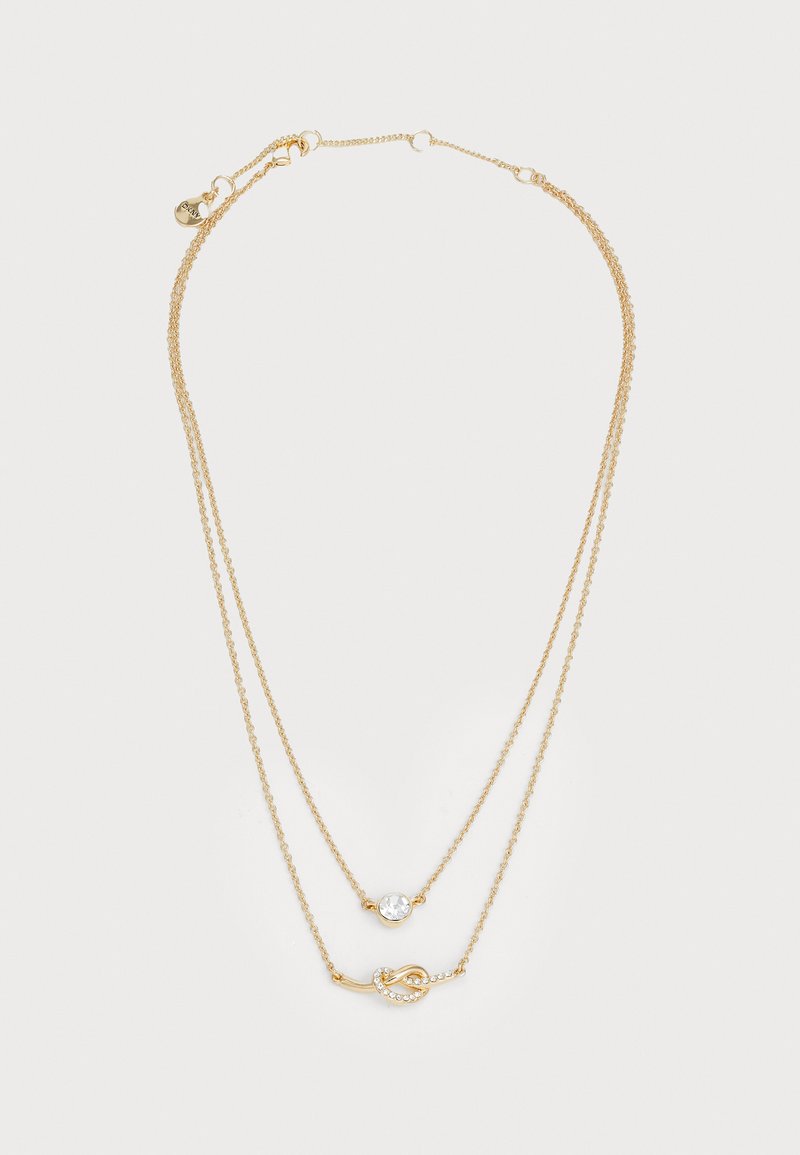 Collana a strati dorata con due catene. Presenta un pendente centrale in cristallo e un accento a nodo decorativo con piccole pietre trasparenti.