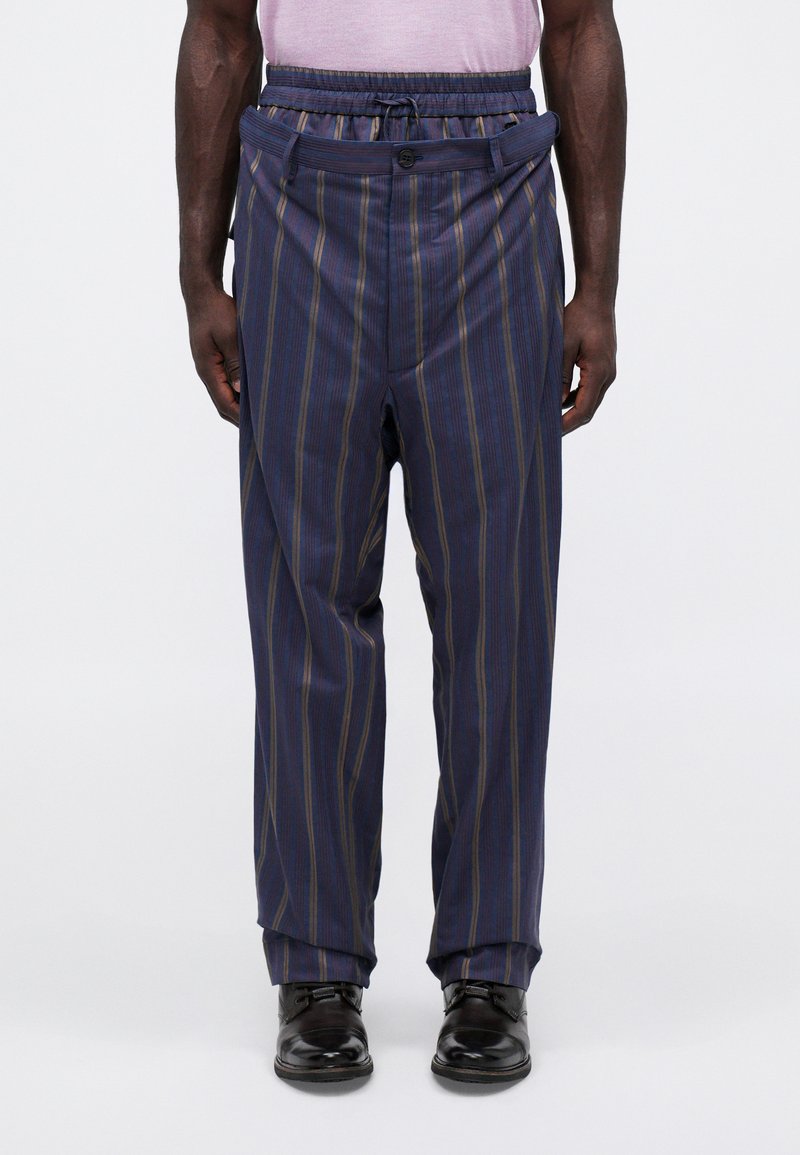 Pantaloni a righe navy con vita elastica, un bottone e orli affusolati. Texture liscia con righe verticali in oro e azzurro chiaro.