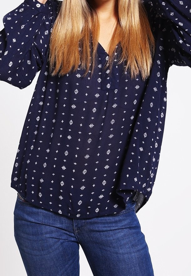 Marinbluse med V-hals og lange ærmer, der har et hvidt mønster af diamanter og sekskanter. Letvægts, flydende stof med en afslappet pasform.