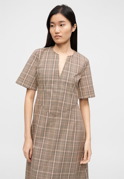 Καφέ φόρεμα με καρό σχέδιο, κοντά μανίκια, V λαιμόκοψη και εφαρμοστή γραμμή στο μπούστο. Το υφασμά του έχει λεπτές μαύρες και πορτοκαλί ρίγες παντού.