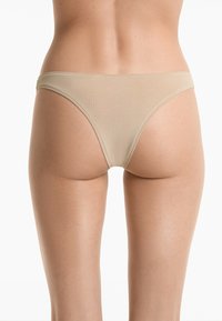 Beige stringondergoed gemaakt van een gladde stof, met een lage taille en minimale bedekking, zonder zichtbare naden of versieringen.