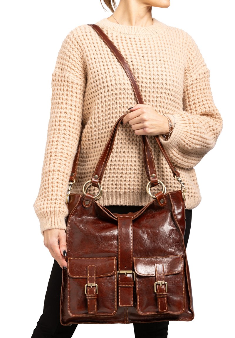 Bruine leren handtas met twee voorzakken, zilveren hardware accenten en een brede schouderband. Glad oppervlak en gestructureerd ontwerp.