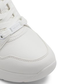 Baskets blanches avec une tige en cuir lisse, bout arrondi et accents texturés. Dotées de lacets blancs et d'une étiquette de marque sur le côté.